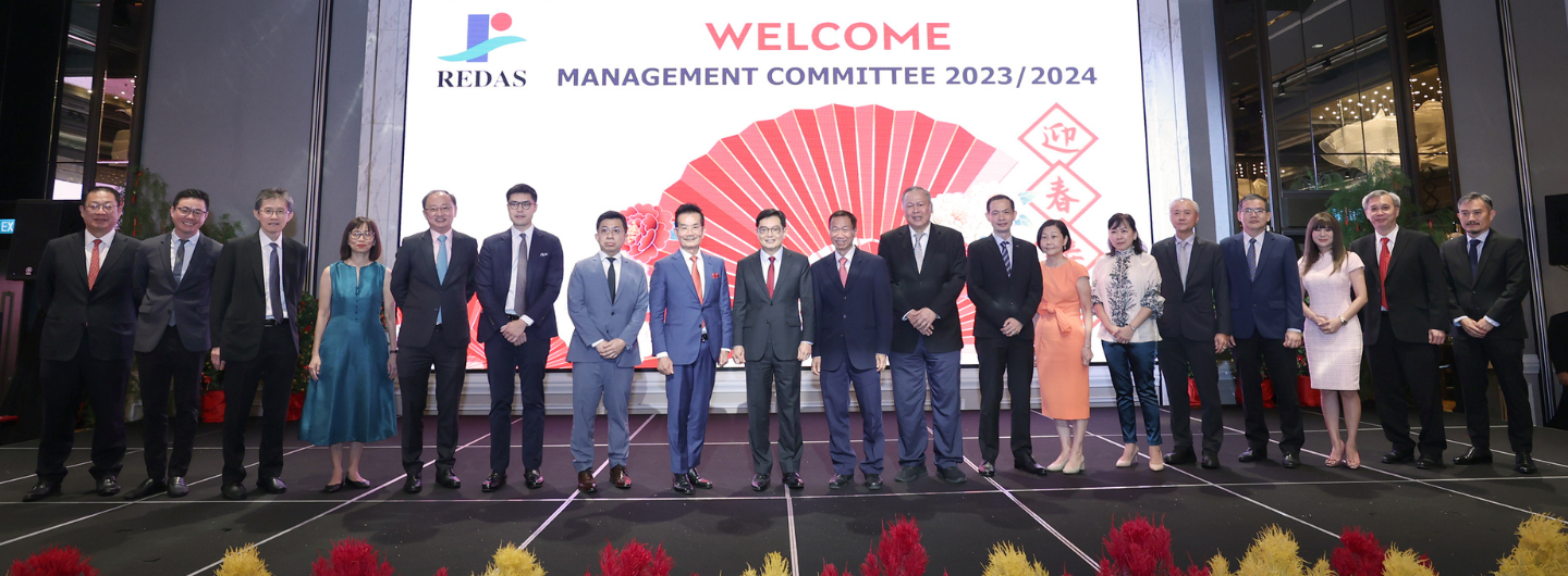 A group of people stand on stage in front of a REDAS welcome banner.